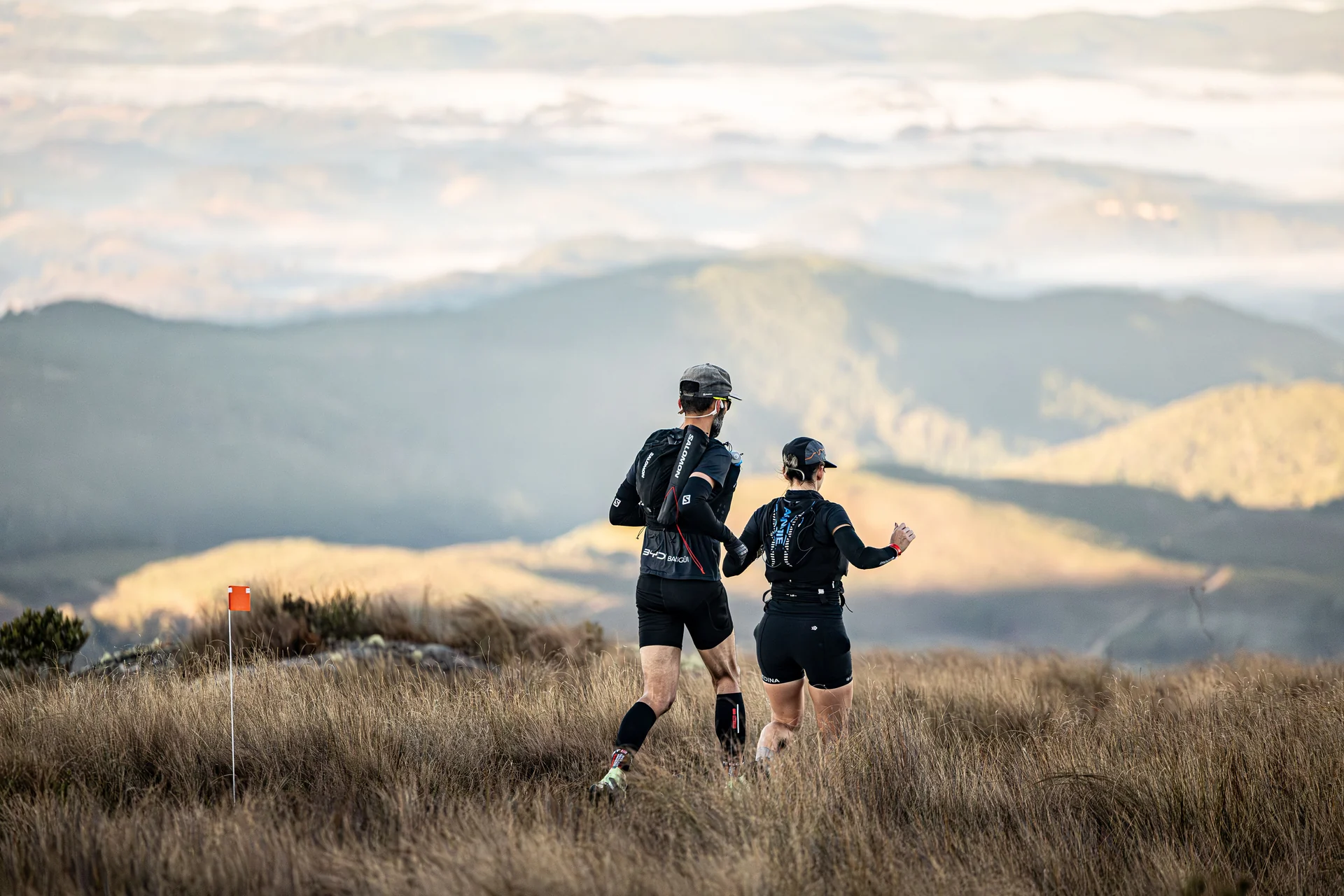 Un corredor y una corredora de trail avanzando juntos por una montaña